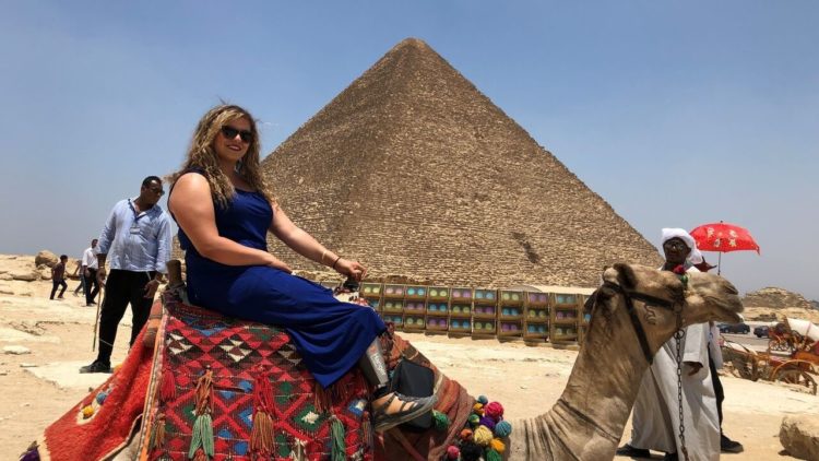 image of woman sitting on a camel in front of a pyramid in Egypt