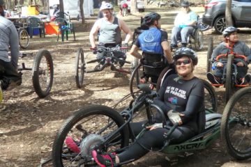a woman sitting in a adapted mountain bike smiling at the camera.